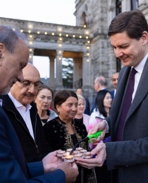 Premier David Eby lights diyas as MLA Harry Bains holds the diyas 