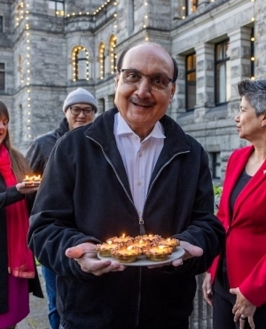 A gleeful Raj Chouhan, Speaker of the House is all smiles holding a plate of lit up diyas 