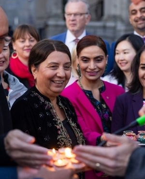 All staff from the BCNDP party gather around Premier Eby as he lights diyas 