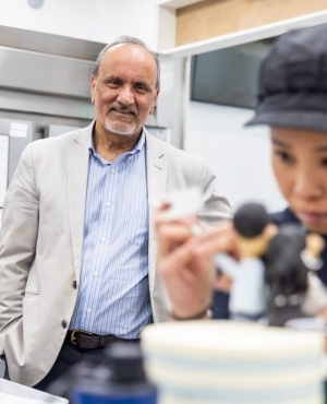 Labour Minister Harry Bains watches as baker decorates cake