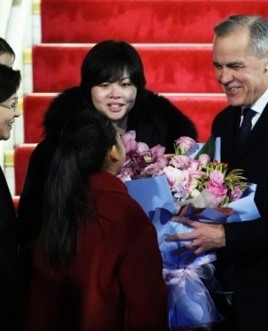 Prime Minister Mark Carney is presented with flowers from Lu You Ci; Courtesy: Canadian Press 