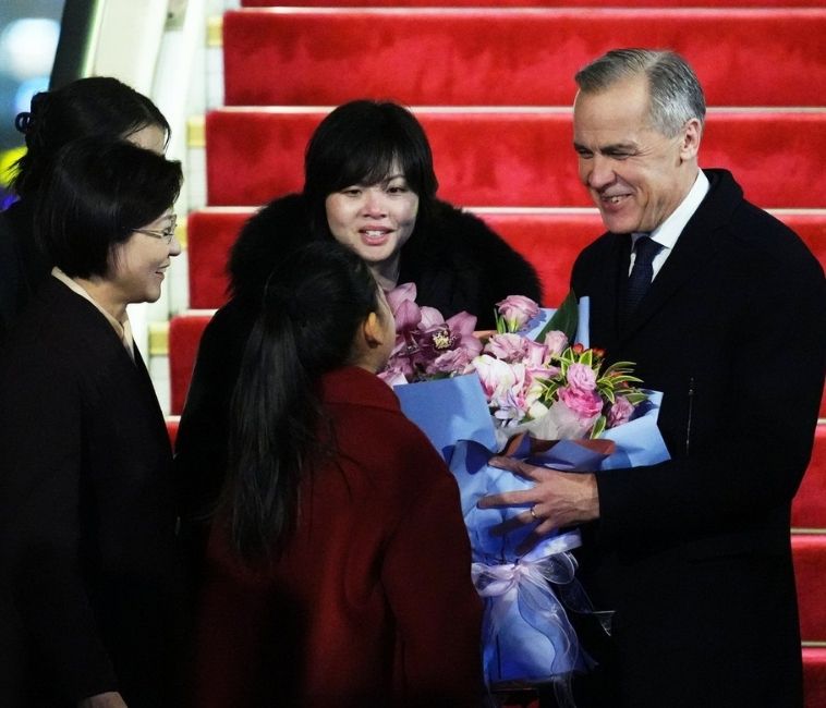 Prime Minister Mark Carney is presented with flowers from Lu You Ci; Courtesy: Canadian Press 