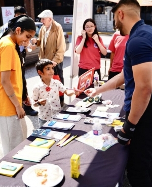 Volunteer hands out a pencil to a child at the drive 